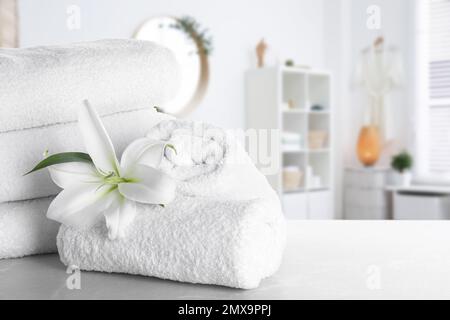 Serviettes fraîches et fleurs de nénuphars sur une table en marbre gris clair dans la salle de bains. Espace pour le texte Banque D'Images