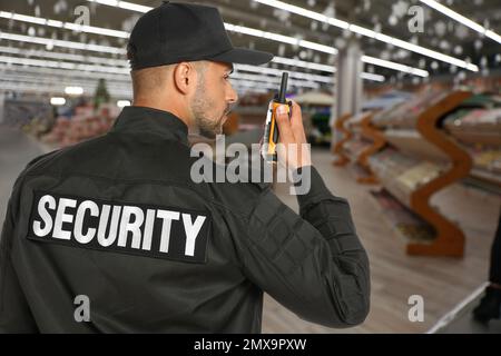 Agent de sécurité utilisant un émetteur radio portable dans le centre commercial Banque D'Images