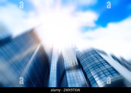 Vue floue du gratte-ciel moderne avec fenêtres teintées sur ciel bleu, vue en angle bas. Société de construction Banque D'Images