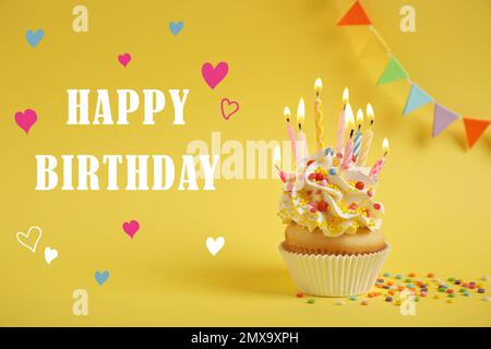 Envoyez un texte « Joyeux anniversaire » et un délicieux cupcake accompagné de bougies allumées sur fond jaune Banque D'Images