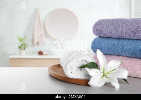 Serviettes fraîches et fleur de nénuphars sur table grise dans la salle de bains. Espace pour le texte Banque D'Images