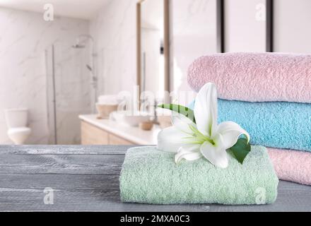 Serviettes fraîches et fleurs de nénuphars sur une table en bois gris dans la salle de bains. Espace pour le texte Banque D'Images