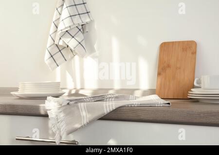 Serviettes en coton, planche et vaisselle sur une table en bois dans la cuisine Banque D'Images