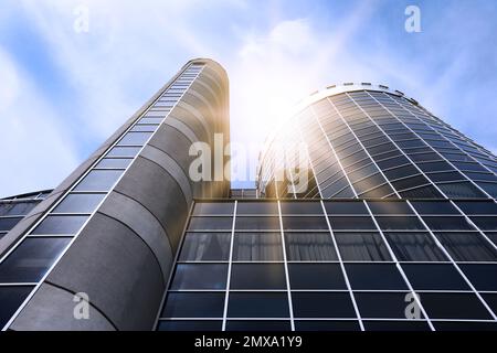 Gratte-ciel moderne avec fenêtres teintées sur ciel bleu, vue en angle bas. Société de construction Banque D'Images