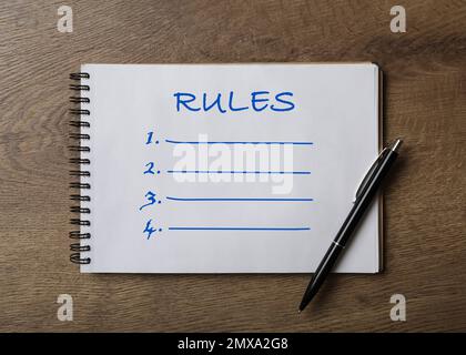 Bloc-notes avec liste des règles et stylo sur table en bois, vue du dessus Banque D'Images