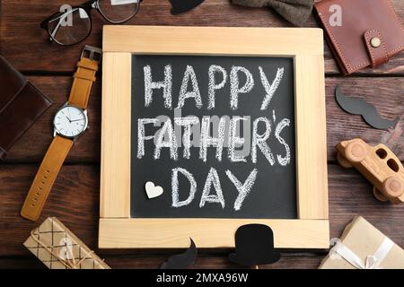Tableau noir avec des mots HAPPY PATHER'S DAY et accessoires masculins sur fond de bois, plat Banque D'Images