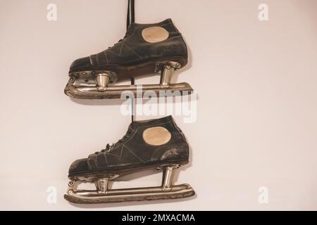 Les vieilles chaussures de patinage sur glace vintage pour hommes sont fixées au mur sur un clou Banque D'Images