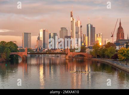 Horizon, gratte-ciels dans le quartier des banques dans la lumière du matin, vieux pont sur le main, rameurs sur la rivière, lever du soleil, automne, Francfort-sur-le-main Banque D'Images