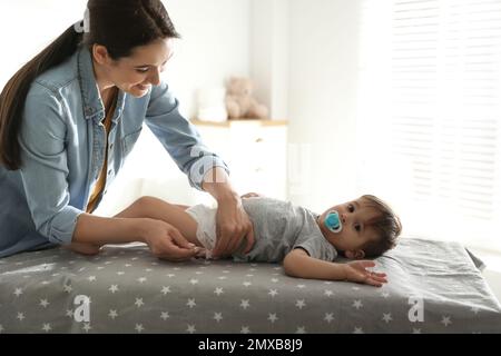 La mère change la couche de bébé sur la table à la maison Banque D'Images