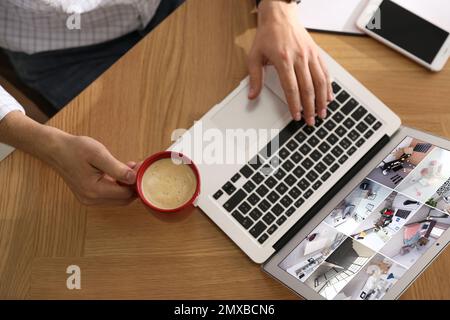 Homme surveillant des caméras cctv modernes sur un ordinateur portable à l'intérieur, vue de dessus. Système de sécurité domestique Banque D'Images