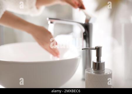 Femme se lavant les mains sur l'évier dans la salle de bains, se concentrer sur le distributeur de savon Banque D'Images