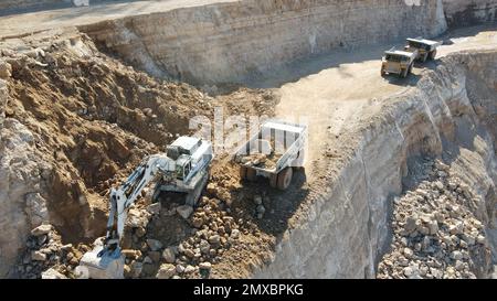 Tombereaux de chargement pour pelles hydrauliques. Ils travaillent sur un immense chantier de construction. Banque D'Images