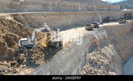 Tombereaux de chargement pour pelles hydrauliques. Ils travaillent sur un immense chantier de construction. Banque D'Images