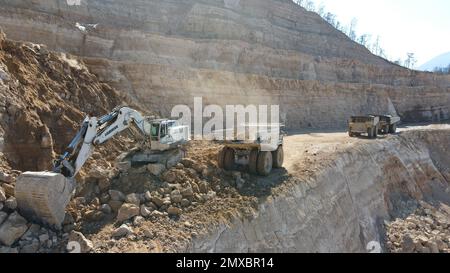 Tombereaux de chargement pour pelles hydrauliques. Ils travaillent sur un immense chantier de construction. Banque D'Images