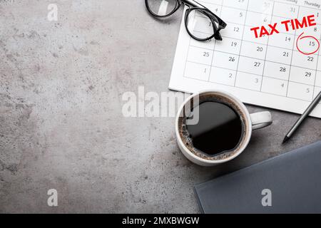 Calendrier avec mots HEURE D'IMPOSITION et tasse de café sur table grise, plat. Espace pour le texte Banque D'Images