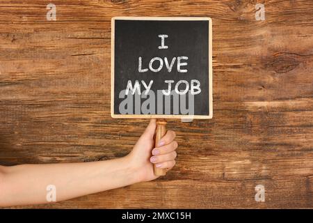 Concept d'engagement des employés. Femme tenant le tableau avec le texte I Love My Job sur fond en bois, gros plan Banque D'Images