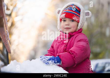 les enfants jouent dans des boules de neige en hiver, vêtus de vestes chaudes Banque D'Images