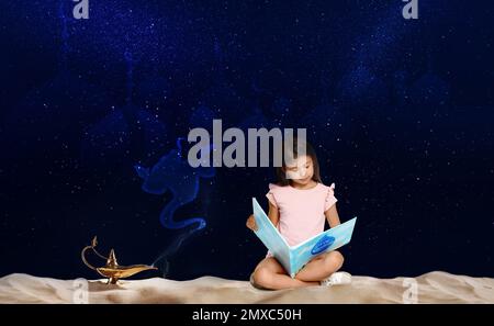 Petite fille mignon lisant le livre magique et la lampe magique Aladdin sur le sable la nuit Banque D'Images