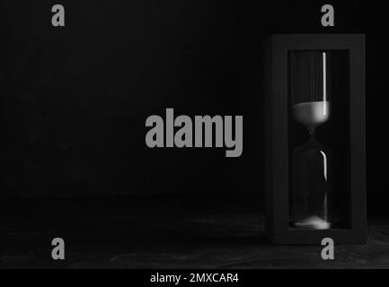 Sablier sur la table sur fond noir, espace pour le texte. Concept de principe de Pareto Banque D'Images