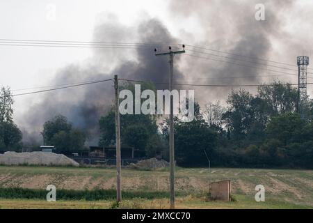 Fumée sortant d'un incendie grave sur une petite propriété industrielle située dans les terres agricoles du Suffolk Banque D'Images