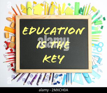 Différents papeterie d'école et petit tableau de surveillance avec formation de phrase EST LA CLÉ sur fond blanc, vue de dessus. Apprentissage des adultes Banque D'Images