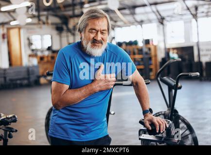 Fitness, gym et vieil homme avec douleur à la poitrine, urgence médicale pendant l'entraînement au studio de sport. Exercice, santé et bien-être, stress et asiatique senior Banque D'Images