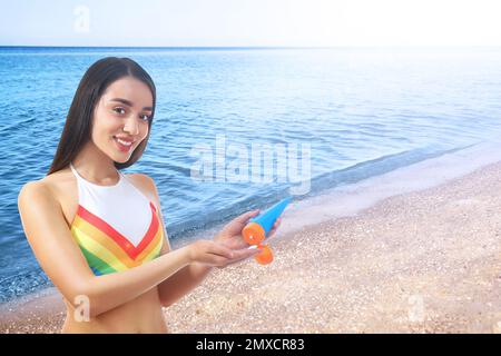 Jeune femme appliquant la crème de protection solaire à la plage, espace pour le texte Banque D'Images