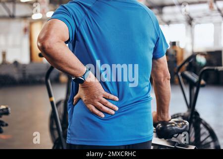 Sports, gym et vieil homme avec douleur à la main sur le dos, urgence pendant l'entraînement au studio de fitness. Santé, bien-être et inflammation, zoom sur la personne âgée Banque D'Images