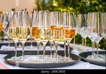 Jardin extérieur avec quelques verres à vin pétillant à moitié remplis sur un plateau Banque D'Images