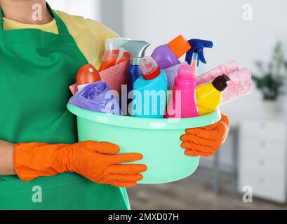 Femme tenant un lavabo avec des fournitures de nettoyage dans le bureau, près Banque D'Images