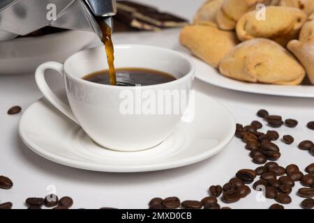 Le processus de verser le café d'une machine à café geyser moka dans une tasse blanche Banque D'Images