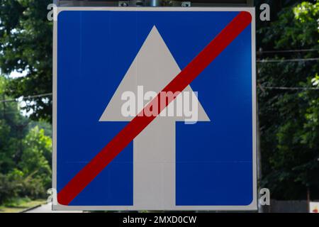 Panneau de route à sens unique, flèche blanche sur fond bleu, barrée d'une ligne rouge sur fond de feuillage d'automne. Maintenant mouvement deux sens dans la rue de ville.Co Banque D'Images