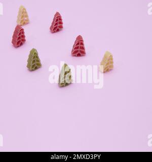 Quelques pâtes colorées du nouvel an en forme d'arbre du nouvel an sur fond rose Banque D'Images