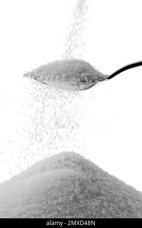 sucre blanc tombant d'une cuillère à café sur un tas de sucre Banque D'Images