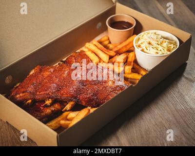 côtes de porc grillées avec frites et sauces dans une boîte à emporter Banque D'Images