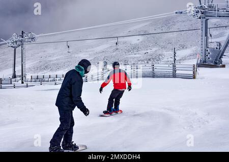 Cairngorm Mountain Aviemore Top Station deux snowboarders qui descendent la pente ou courent Banque D'Images