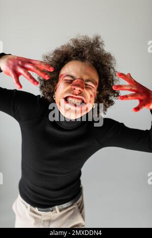 maltraité et blessé africain américain avec le visage saignant et le nez cassé grimacing isolé sur gris, image de stock Banque D'Images