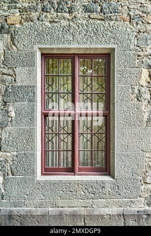 Vieilles fenêtres avec grilles en fer forgé sur le mur en pierre du bâtiment historique. Le château médiéval aux murs restaurés attire l'attention des visiteurs Banque D'Images