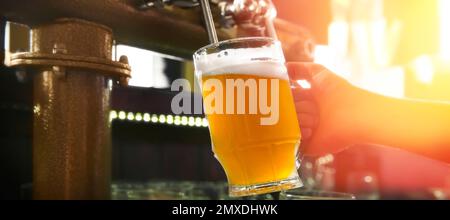 Barman versant de la bière du robinet dans le verre dans le bar, gros plan. Bannière Banque D'Images