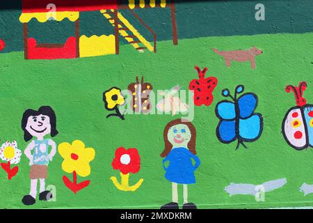 Murale peinte sur un mur extérieur d'enfants et de fleurs. Banque D'Images