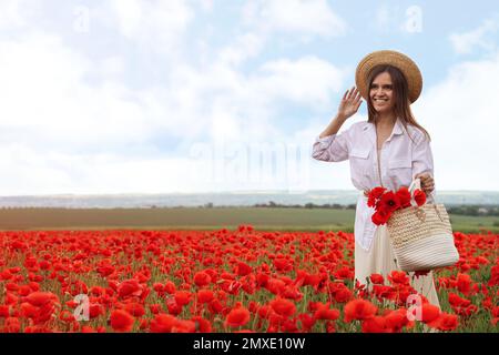 Femme tenant un sac à main avec des fleurs de pavot dans un beau champ Banque D'Images