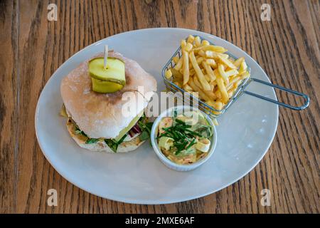 Hamburger intérieur au café avec frites et coleslaw servi sur une assiette blanche Banque D'Images