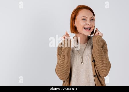 Femme joyeuse aux cheveux rouges montrant oui geste isolé sur gris, image de stock Banque D'Images