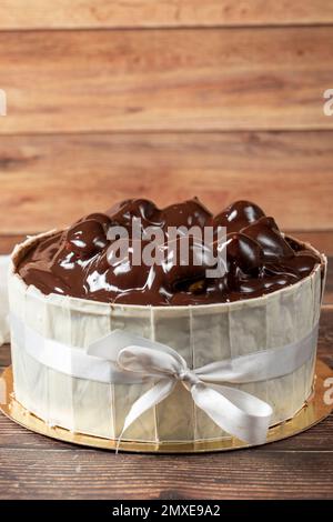 Gâteau au profiterole. Gâteau aux profiteroles entouré de chocolat blanc sur fond de bois. gros plan Banque D'Images