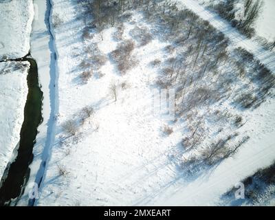 Vue aérienne d'une rivière gelée dans une forêt enneigée Banque D'Images