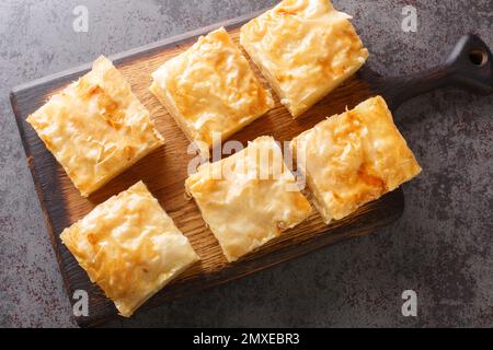 Délicieuse pâtisserie grecque sucrée Galaktoboureko, faite de crème anglaise semoule en filo sur le panneau en bois de la table. Vue horizontale du dessus Banque D'Images