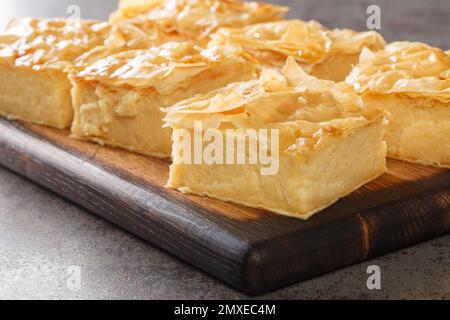 Délicieuse pâtisserie grecque sucrée Galaktoboureko, faite de crème anglaise semoule en filo sur le panneau en bois de la table. Horizontale Banque D'Images