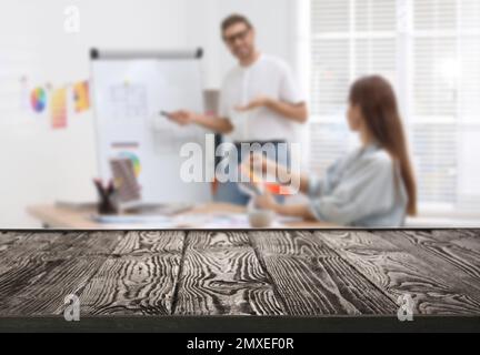 Surface en bois vide et vue floue des designers d'intérieur professionnels travaillant au bureau, en gros plan. Espace pour le texte Banque D'Images