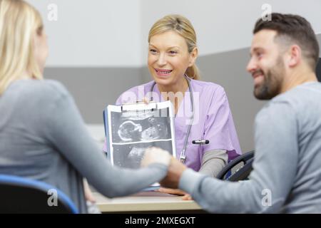 le médecin explique le résultat de l'échographie au couple asiatique à l'hôpital Banque D'Images