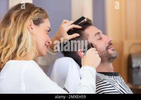 homme se couper les cheveux par une femme Banque D'Images